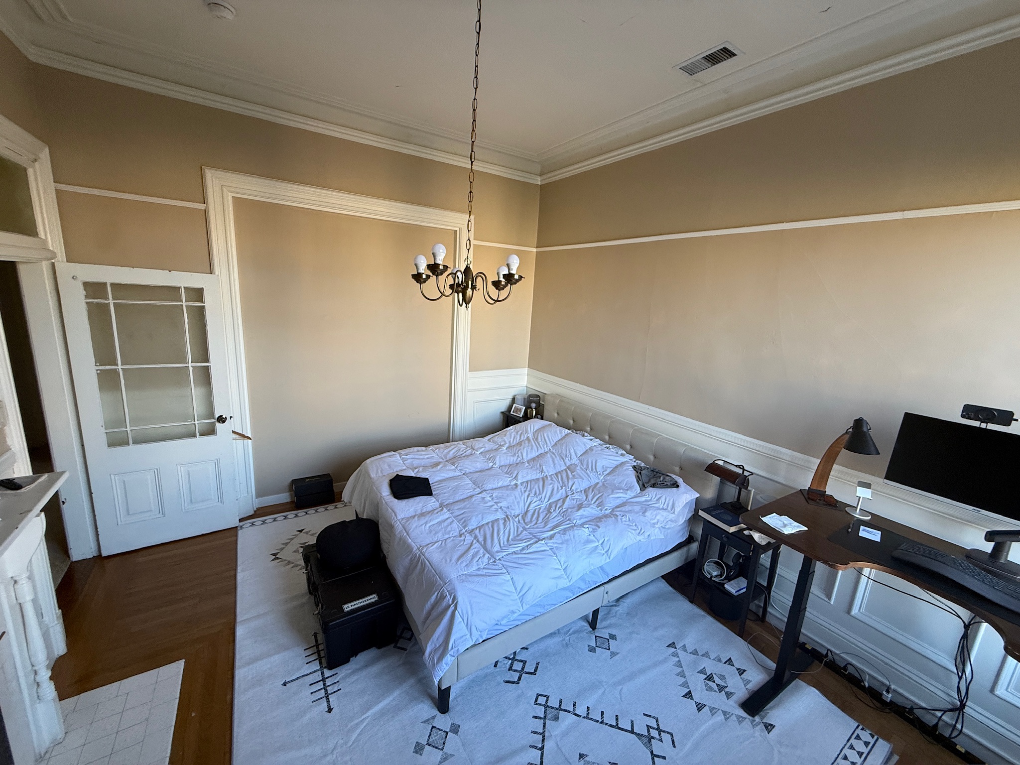 Spacious bedroom with fireplace, chandelier, and geometric rug
