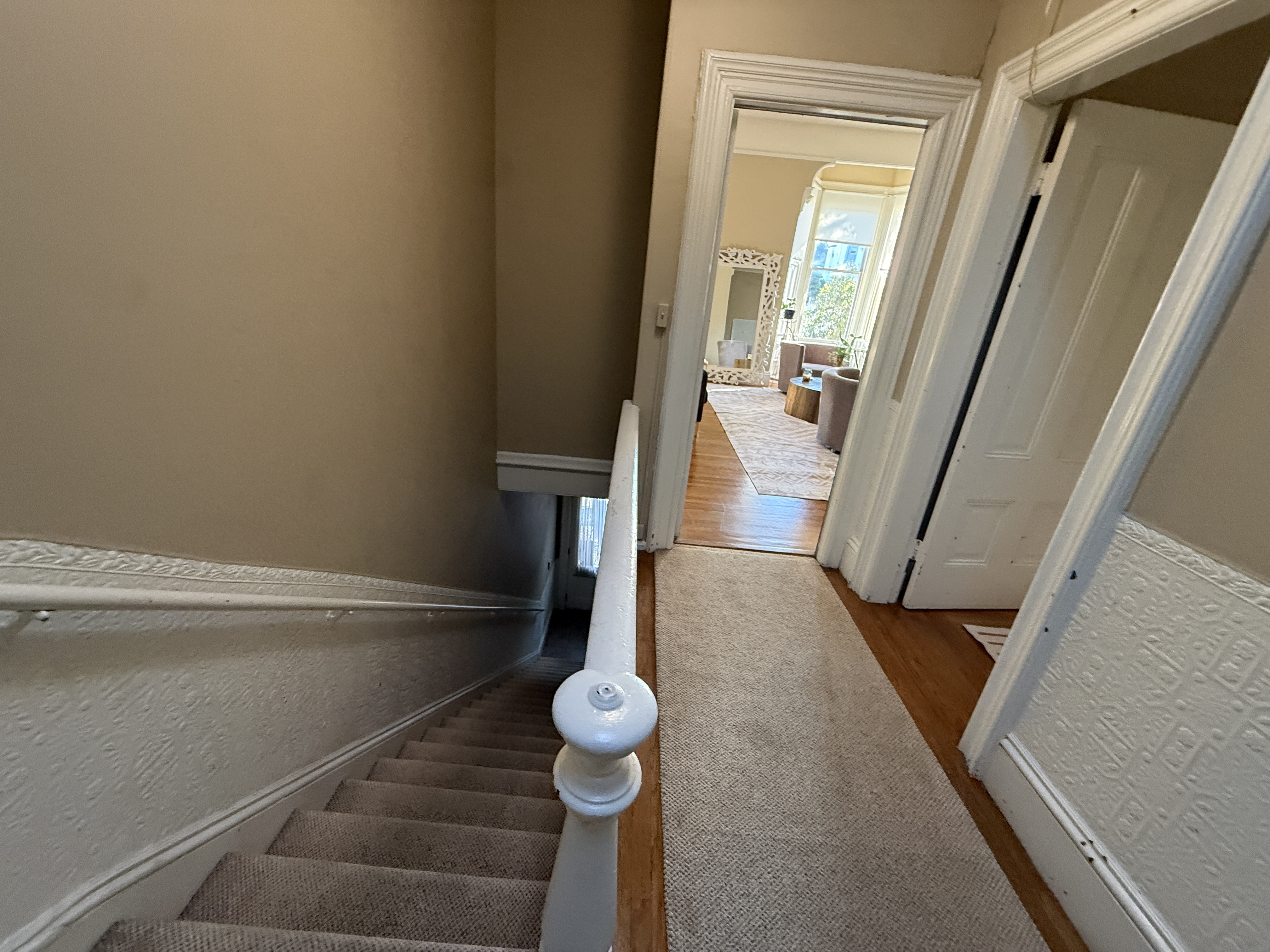 Carpeted staircase and hallway with view to living room