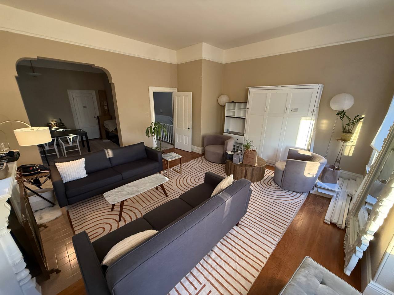 Living room with murphy bed closet, multiple couches and staircase